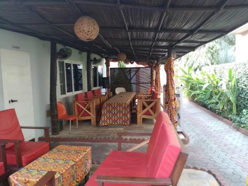 un portico con sedie rosse, tavolo e sedie di Residence Ivoire Cotonou a Cotonou