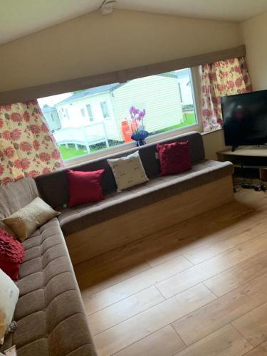 a couch in a living room with a window at DaisyChain 2 Getaways - The perfect place to Stay - Play - Getaway in East Mersea