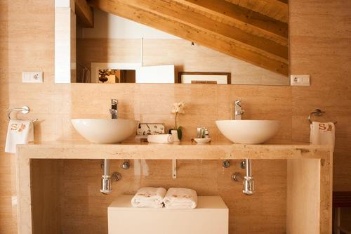uma casa de banho com 2 lavatórios numa parede de madeira em Sotobosque em Mortera