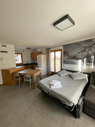 a bedroom with a bed and a table and a kitchen at Mansarda Tresero- Residenza Vallecetta 2 in Piatta