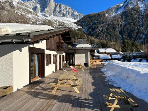 um edifício com um deque de madeira com montanhas cobertas de neve em Chalet Pleine Vue & Spa em Chamonix-Mont-Blanc