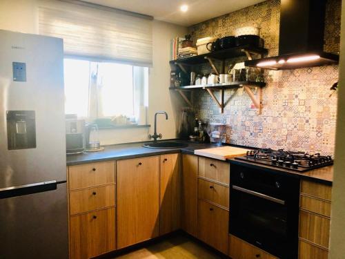a kitchen with wooden cabinets and a black stove top oven at Apartament na Okulickiego - Centrum !! in Stalowa Wola