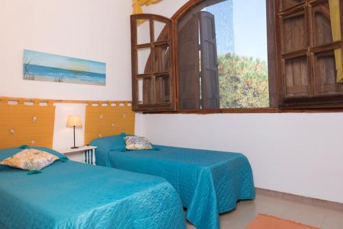 Habitación con 2 camas azules y ventana. en Le Sunrise - Appartamenti a 350 mt dal mare e con giardino privato, en Cala Liberotto