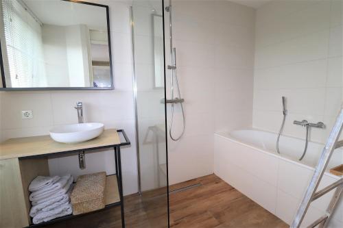 a bathroom with a sink and a bath tub at Beach House 76 in Cadzand