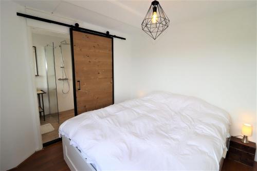 a bedroom with a white bed and a wooden door at Beach House 76 in Cadzand