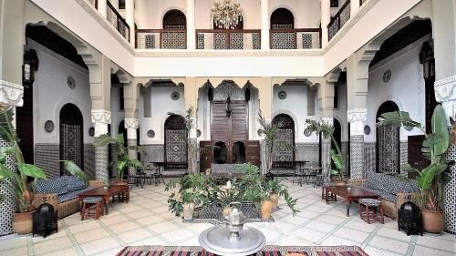 a large lobby with tables and chairs and plants at Riad Razane Fez in Fez