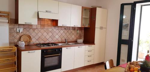 a kitchen with white cabinets and a stove top oven at Le Caracol - Appartamenti immersi nel verde della campagna e a 1 chilometro da Orosei in Orosei