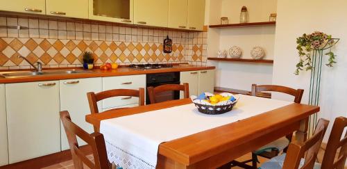 a kitchen with a table with a bowl of fruit on it at Le Caracol - Appartamenti immersi nel verde della campagna e a 1 chilometro da Orosei in Orosei