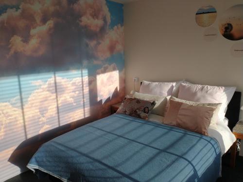 een slaapkamer met een bed en een schilderij van wolken bij B&Bslapenopeeneiland in Kaag