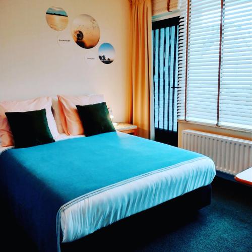 a bedroom with a large blue bed with a window at B&Bslapenopeeneiland in Kaag