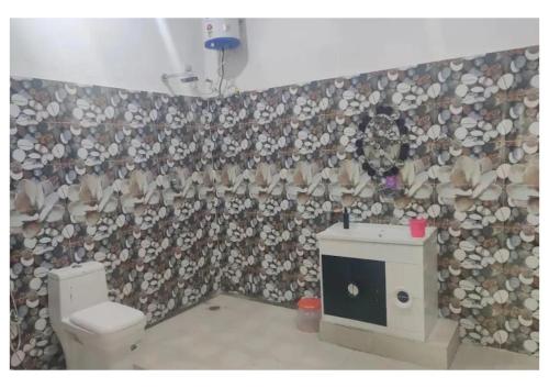 een badkamer met een toilet en een muur bedekt met houtblokken bij CasaBlanca 5BHK in Dehradun