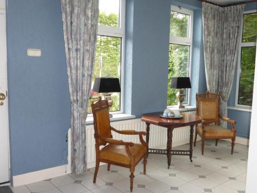 a dining room with a table and chairs and windows at B&B Berkenrode in Rockanje