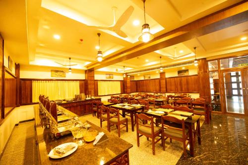 un restaurante con mesas y sillas de madera y techo en Hotel Guruvayur Darshan en Guruvāyūr