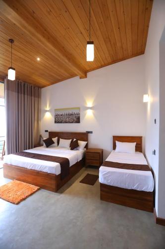 two beds in a bedroom with wooden ceilings at Icy Falls - Ohiya in Ohiya