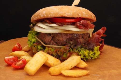 a large sandwich and french fries on a wooden plate at Hotel Haus Wiesengrund in Hallenberg