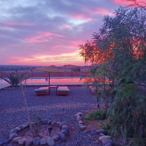 a bench in a park with a sunset in the background at LESCALE DE OUARZAZATE in Ouarzazate