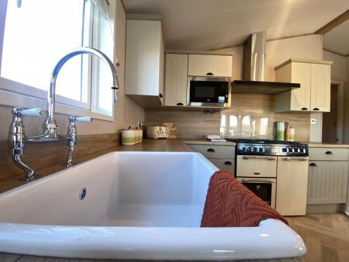 una cocina con un gran fregadero blanco en Daphne's Lodge, en Mawgan Porth