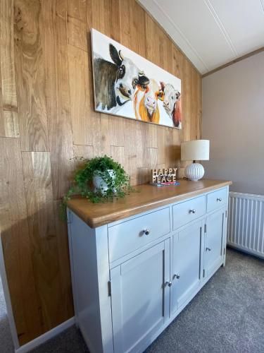 a white cabinet in a room with a painting on the wall at Daphne's Lodge in Mawgan Porth