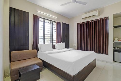 een slaapkamer met een groot wit bed en een stoel bij Hotel Nova Vatika in Surat