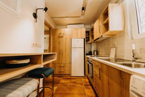 a small kitchen with wooden cabinets and a white refrigerator at Loutraki Hidden Gem Ι in Loutraki