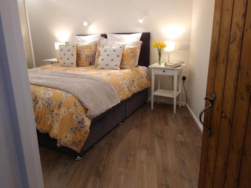 ein Schlafzimmer mit einem Bett und einem Tisch mit Blumen darauf in der Unterkunft The Nook Cottage In The Heart Of Northumberland in Wark