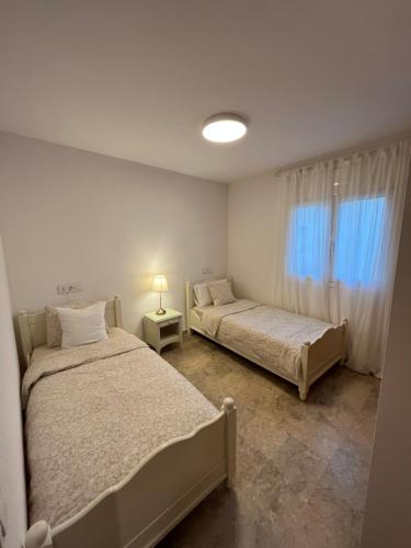 sypialnia z 2 łóżkami, lampką i oknem w obiekcie Apartamento luminoso Paloma a 350 metros de la playa con parking gratuito w Sant Feliu de Guixols