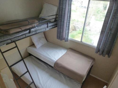 シジャンにあるSIGEAN Mobil Home dans Camping Tohapiの二段ベッド2台、窓が備わる小さな客室です。