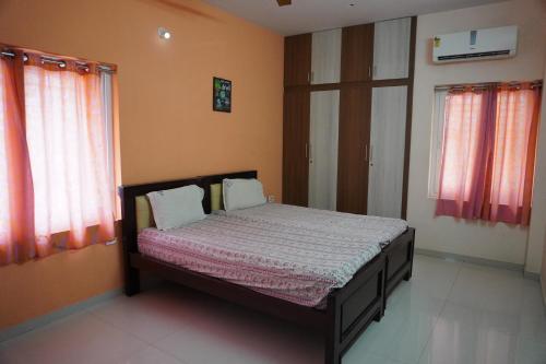 a small bed in a room with two windows at RBS NEST in Tiruchchirāppalli