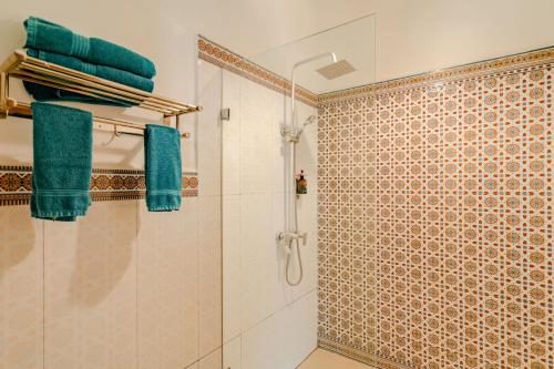 a bathroom with a shower with blue towels on a wall at Kendwa Rocks Hotel in Kendwa