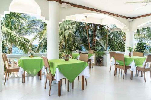 a restaurant with green tables and chairs and palm trees at The Beach House Carabao Island in San Jose