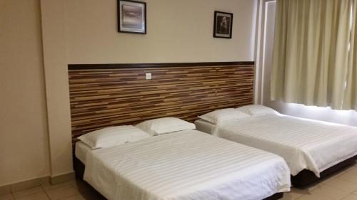 twee bedden naast elkaar in een slaapkamer bij Hotel Sri Iskandar in Kota Kinabalu