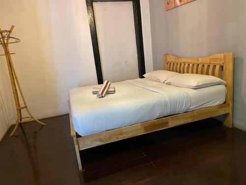 a bed with a wooden frame with a towel on it at Layang Layang Guest House Melaka in Melaka