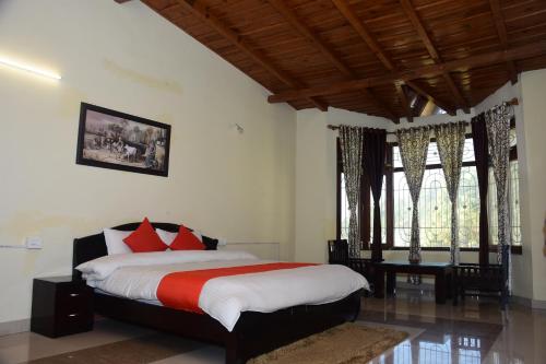 a bedroom with a bed with red and white pillows at Hotel Goludev Valley View in Nainital
