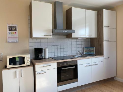 a kitchen with white cabinets and a microwave at Ferienwohnungen Koch EG adult only in Wangerland