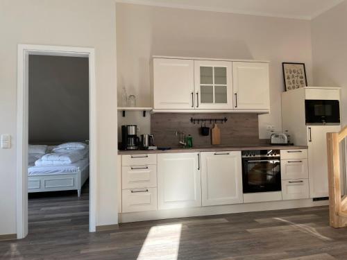 a kitchen with white cabinets and a bed in a room at Café Ilse - Ferienwohnungen in Ranis