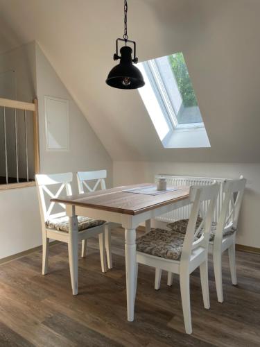 a dining room table with white chairs and a window at Café Ilse - Ferienwohnungen in Ranis