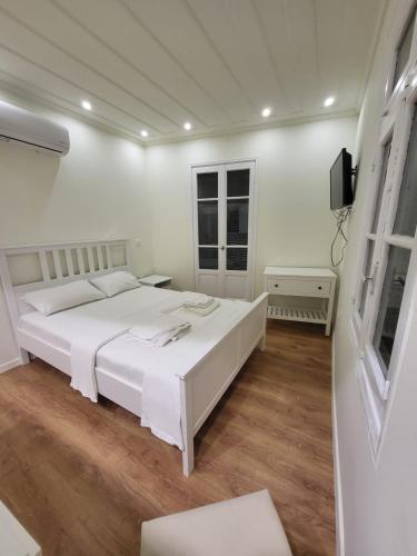 Un dormitorio blanco con una cama blanca y un televisor. en Lefkada Triola Apartments, en Lefkada