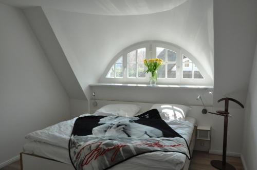 1 dormitorio con 1 cama con ventana y un jarrón de flores en Ferienhaus Haubenlerche 63 - Haus Marilyn en Fuhlendorf