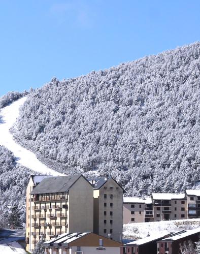 a building in front of a snow covered mountain at Le Petit Ours & Le Petit Cerf - Studios vue lac & montagnes in Les Angles
