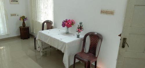 Jestine Homestay في كوتشي: طاولة عليها كرسيين و مزهرية ورد