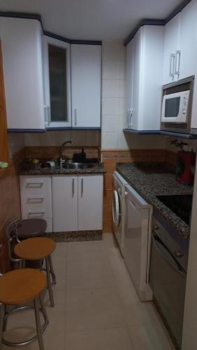 a kitchen with white cabinets and a sink and a stove at Apartamento Medina in El Morche