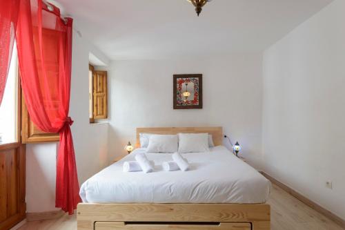 a bedroom with a white bed with a red curtain at Esmeralda's House in Granada