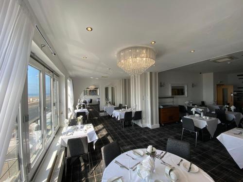 a restaurant with white tables and chairs and a chandelier at The Strand Hotel in Blackpool