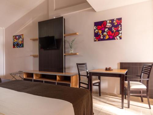 a room with a bed and a table and a tv at Palma Real Posada in Puerto Iguazú