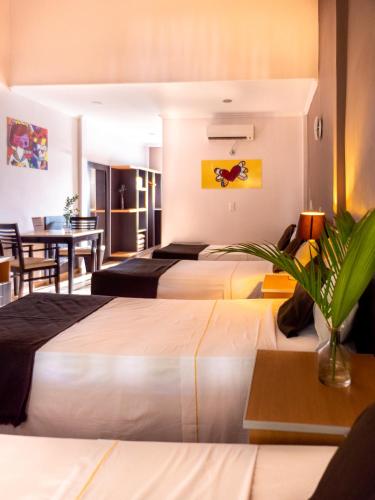 a hotel room with three beds and a table at Palma Real Posada in Puerto Iguazú