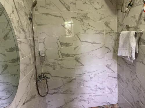 a bathroom with a shower with white marble tiles at Bonsukoda Lodge in Accra