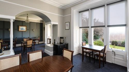a waiting room with tables and chairs and windows at Sunbank House Metro Hotel in Perth