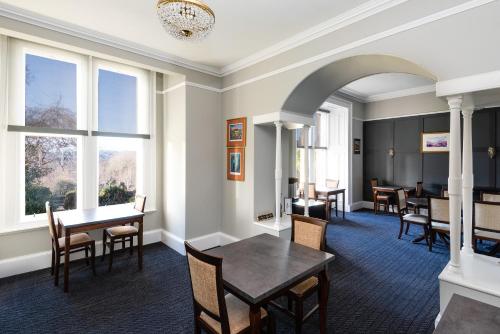 a dining room with tables and chairs and windows at Sunbank House Metro Hotel in Perth