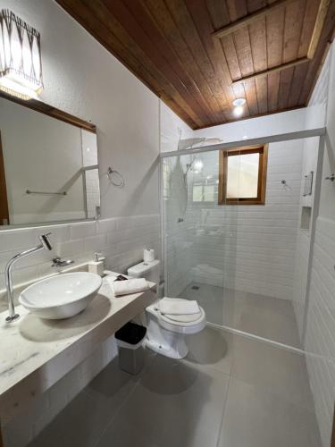 a bathroom with a sink and a toilet and a mirror at La Bella Suítes in Ilhabela