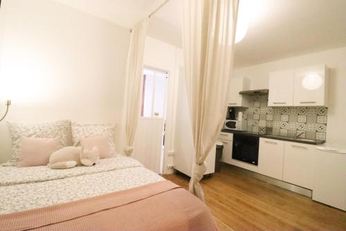 a white bedroom with a bed and a kitchen at Appartement Scandinave proche Cathédrale in Reims